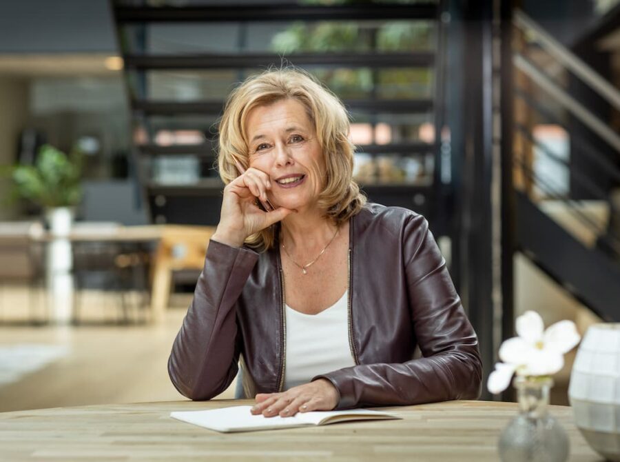 Portret van teamcoach Ine van den Heijkant aan een bureau in de houding van de denker